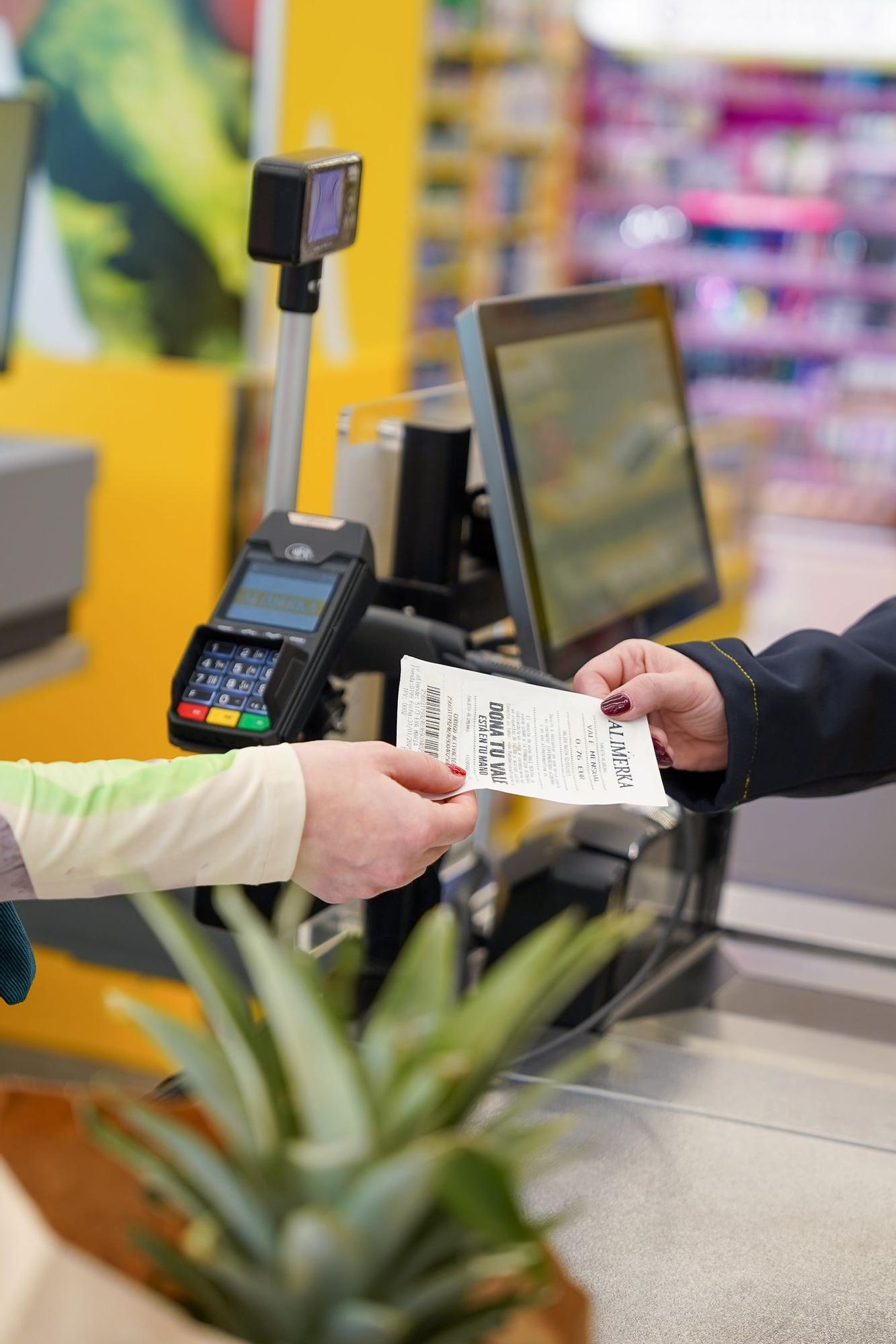 Clientes donando vales de descuento en supermercados Alimerka para apoyar proyectos sociales.