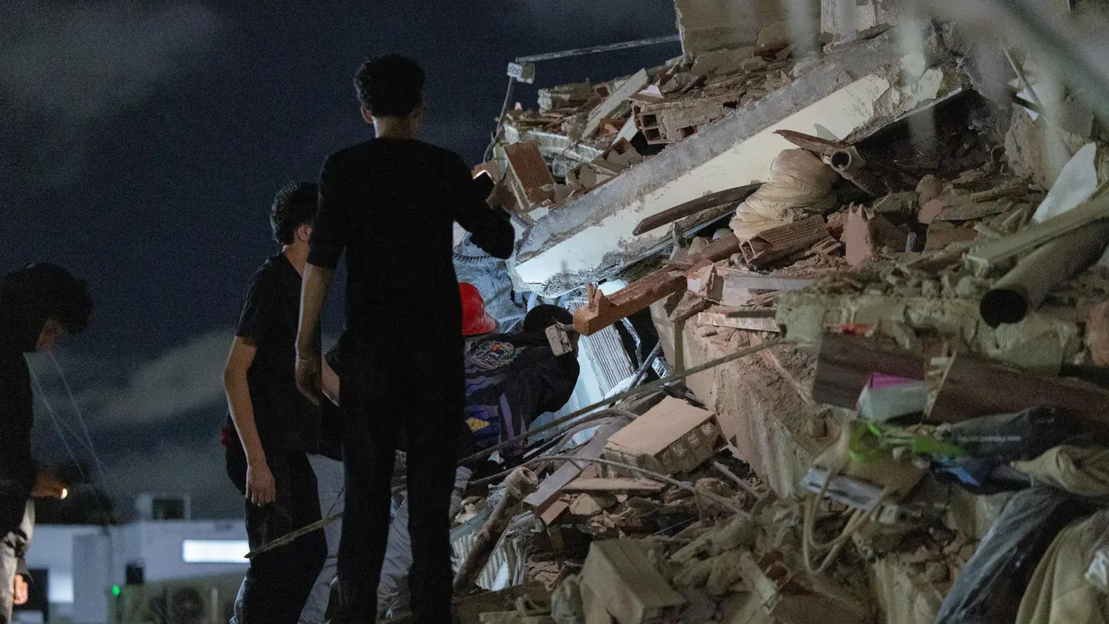 Imagen de edificios colapsados y calles destrozadas tras un terremoto en Venezuela, con servicios de emergencia trabajando en la zona.