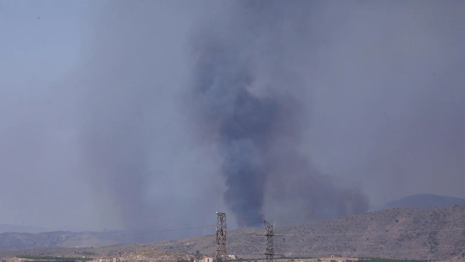 Efectivos de bomberos trabajando en la extinción de un gran incendio forestal en una zona rural.