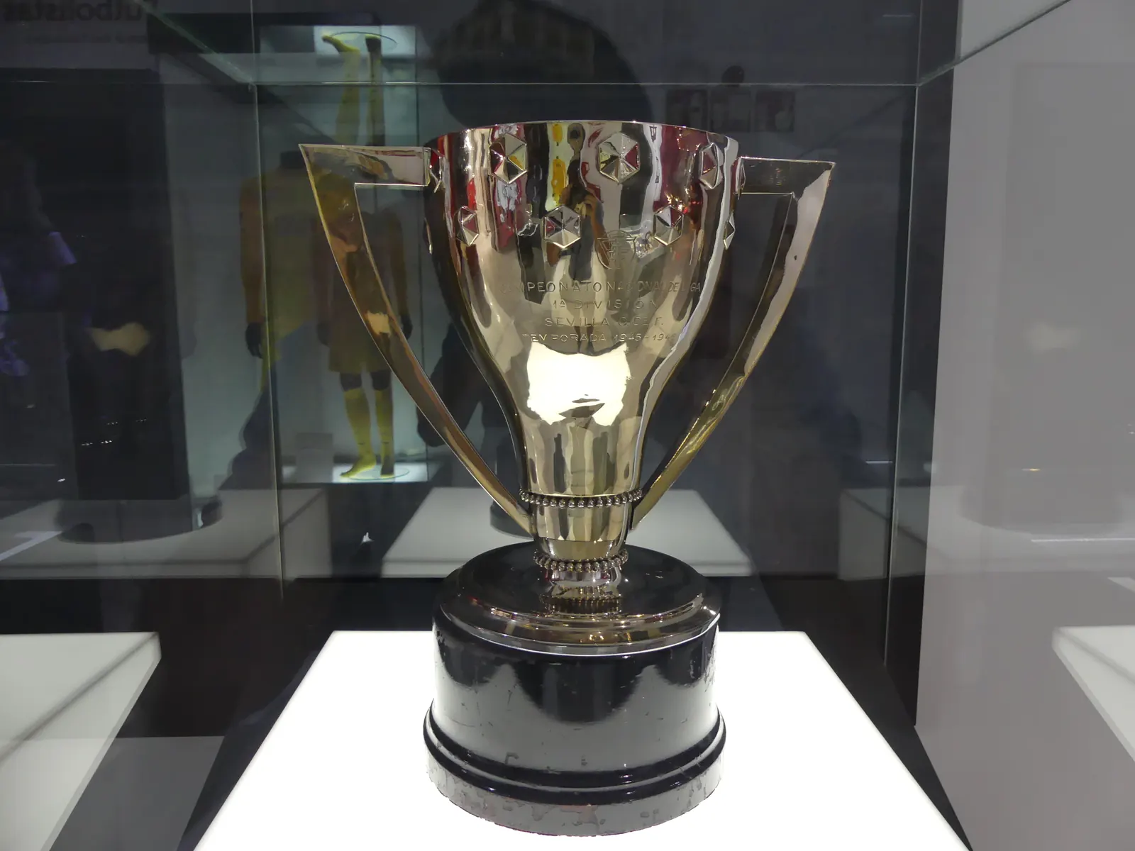 Trofeo de La Liga con un estadio de fútbol al fondo