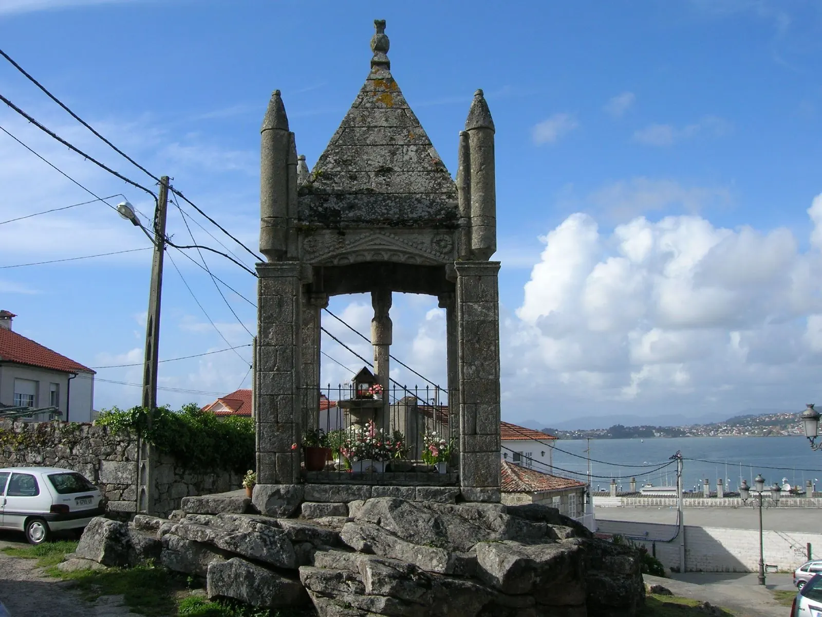 Vista de Baiona con cielo parcialmente nublado y sol asomando.